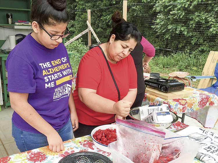 Rohelia and Fatima, both parents of Burch Elementary students, help prepare the strawberries used to make jam. Photo/Sandy Golden.
