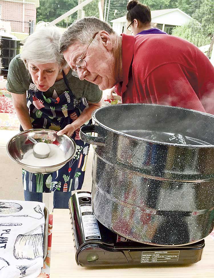 Hopewell UMC members Janet Lester and Bob Golden carefully measure out the right amount of sugar to be used in canning the strawberries. Photo/Sandy Golden.