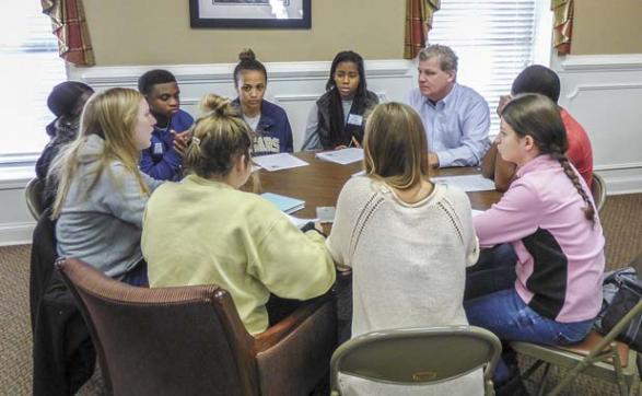  Nearly 50 teens from AVPRIDE got a look at how local government works in a Dec. 10 meeting with administrators at the old courthouse in Fayetteville. Fayette County Administrator Steve Rapson (in blue shirt, top right) listens to a student’s question during a small group session. Photo/Ben Nelms.