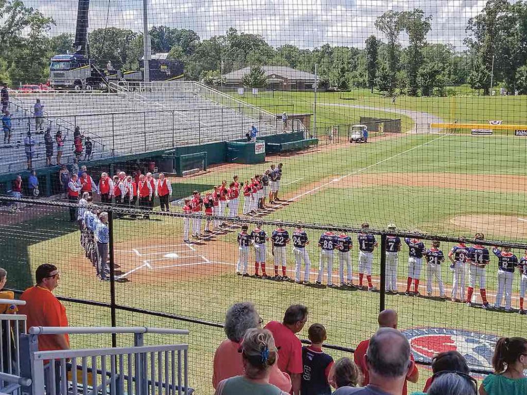 Little League players, coaches and fans stand for the National Anthem. Photo/Ken Miller.