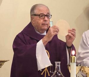 Father Paul Massey administering the Eucharist in 2019.