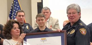 Backed by members of the Peachtree City Police Department, Mayor Vanessa Fleisch (L) and Chief Janet Moon display the award announcing the department's recent accreditation again by CALEA. Photo/Cal Beverly.