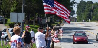 Patriotism was alive and well in Fayetteville on July 4, as members of Fayette County American Legion Post 105 lined South Glynn Street in front of the Log Cabin, waving flags and being recognized by the many motorists honking their horns in support. Photo/Ben Nelms.