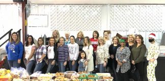 Theresa Clay (front, center in the gray "Merry Christmas Y'all" sweatshirt) and most of her 19-member "elf crew" prepare to load their homemade Christmas goodies into 93 boxes to ship to troops overseas. Photo/Submitted.