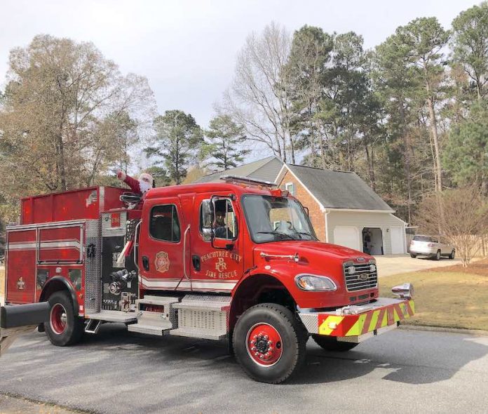 The jolly elf in the red suit was conveyed through Peachtree City neighborhoods Sunday courtesy of the Peachtree City Fire Department. His reindeer were unavailable for comment on the antique mode of transportation. Photo/Joyce Beverly.