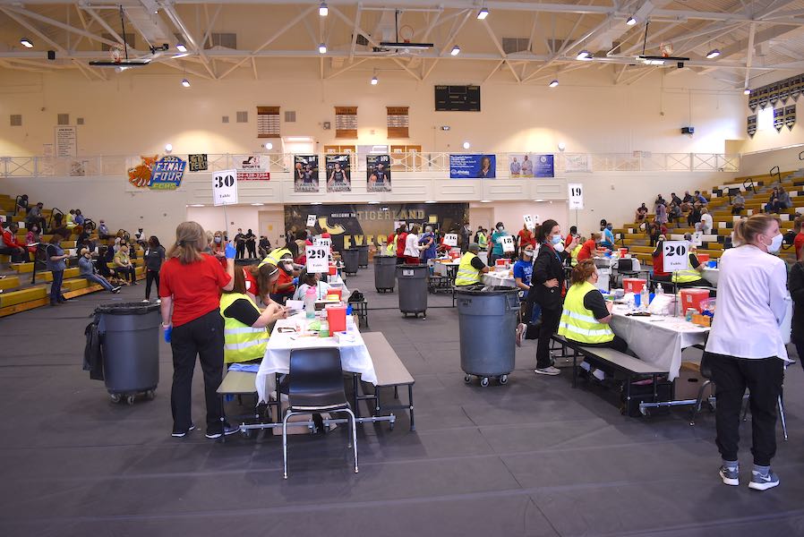 <b>The gym floor housed 30 tables staffed by two school nurses each and other helpers to prepare school workers for the Covid-19 injections. Photo/Cal Beverly.</b>