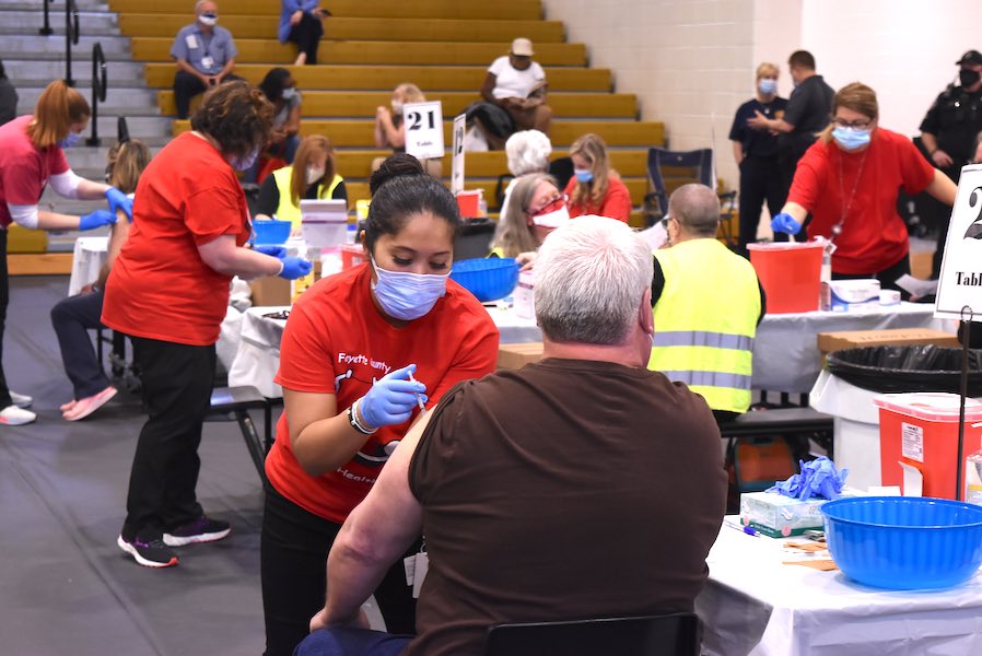 Fayette County School System nurses (in red pullovers) vaccinate system employees at a mass Covid-19 immunization event March 11 at the Fayette County High School Gymnasium. Photo/Cal Beverly.