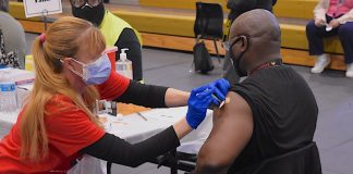 A Fayette County School System nurse injects an employee with the first dose of the Covid-19 vaccine at one of 30 stations on the floor of Fayette County High School Gymnasium March 11. Photo/Cal Beverly.