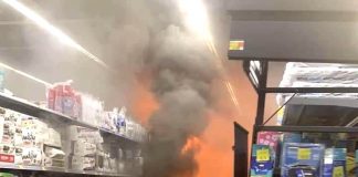 Flames shoot from a rack on the aisle containing paper products like toilet paper and paper plates toward the rear of the Walmart Superstore in Peachtree City. The photo was taken moments after the fire blazed up and was shared on the Peachtree City Police Department's Facebook page.