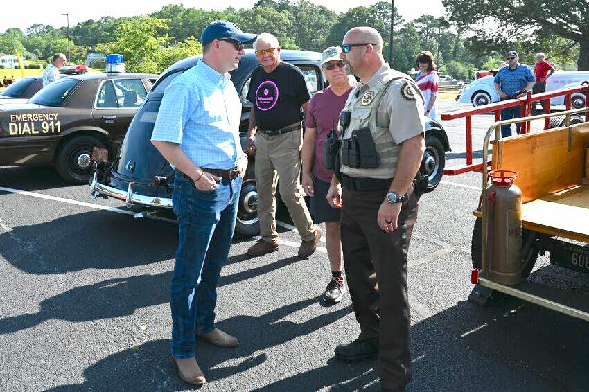 Pastor Josh Saefkow (L, with blue baseball cap) talks with Fayette County Sheriff Barry Babb during the church's car and craft show in June 2023 at the church on Flat Creek Trail. Photo/Roger Alford.