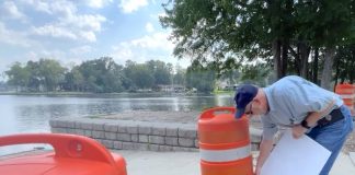 City worker on Friday removes sign warning against swimming in Lake Peachtree. Photo?Peachtree City Facebook page.