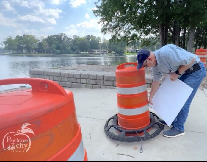 City worker on Friday removes sign warning against swimming in Lake Peachtree. Photo?Peachtree City Facebook page.