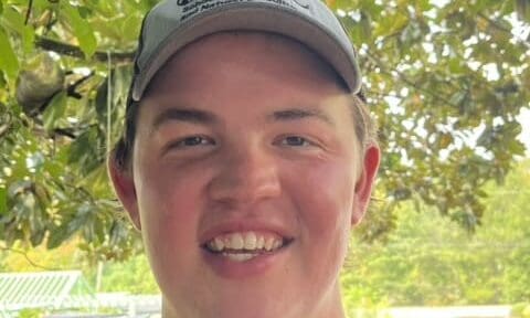 Smiling man in an ABAC cap outdoors under a magnolia tree