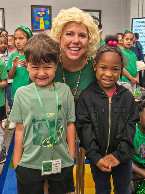 A staff member in a Dolly Parton wig poses with two students
