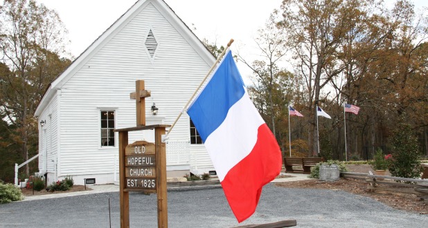 French flag flies in front of church